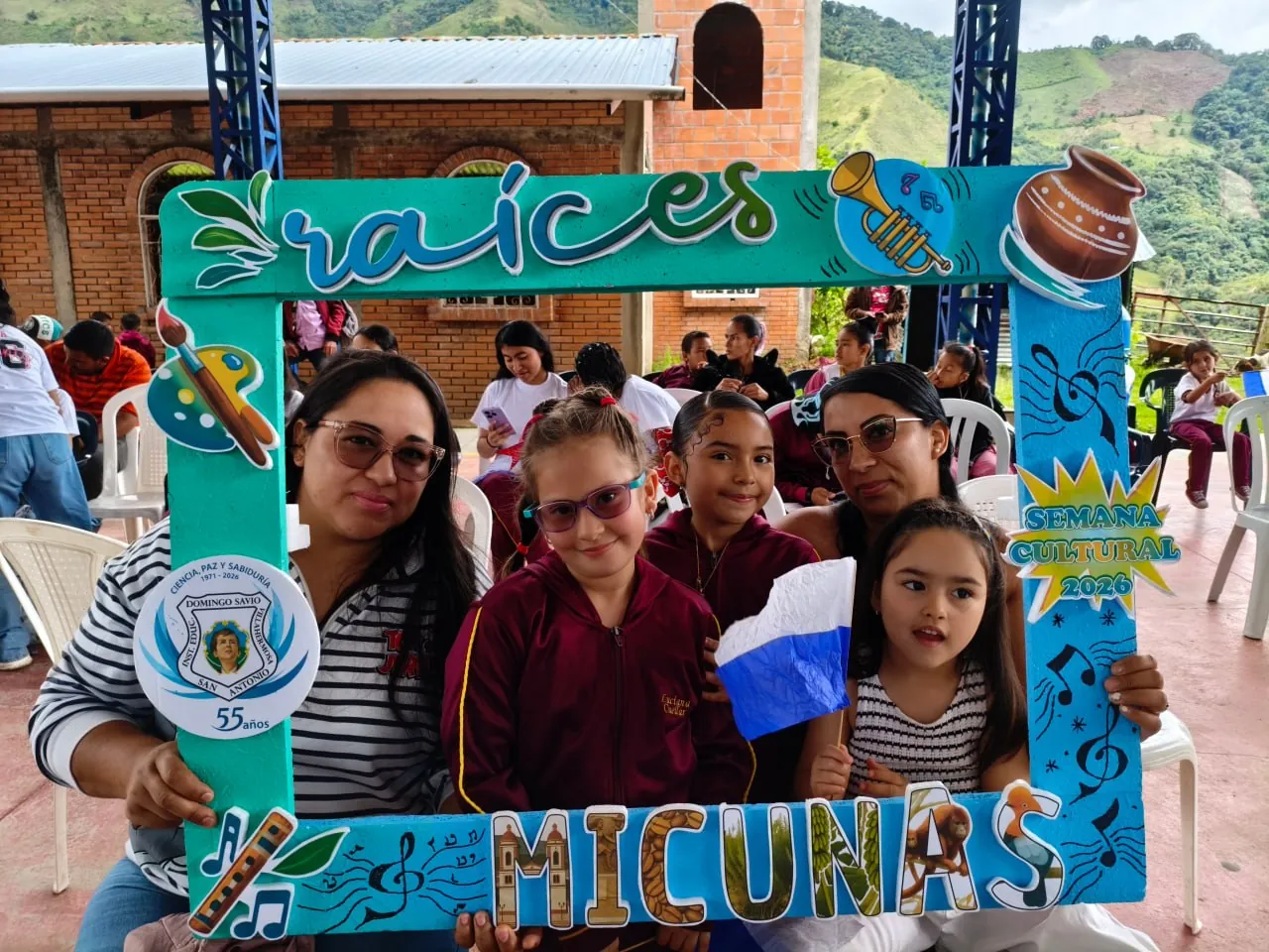 Madres de familia con estudiantes y la bandera institucional